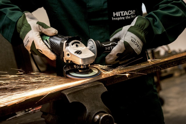 person-holding-black-and-gray-hitachi-angle-grinder